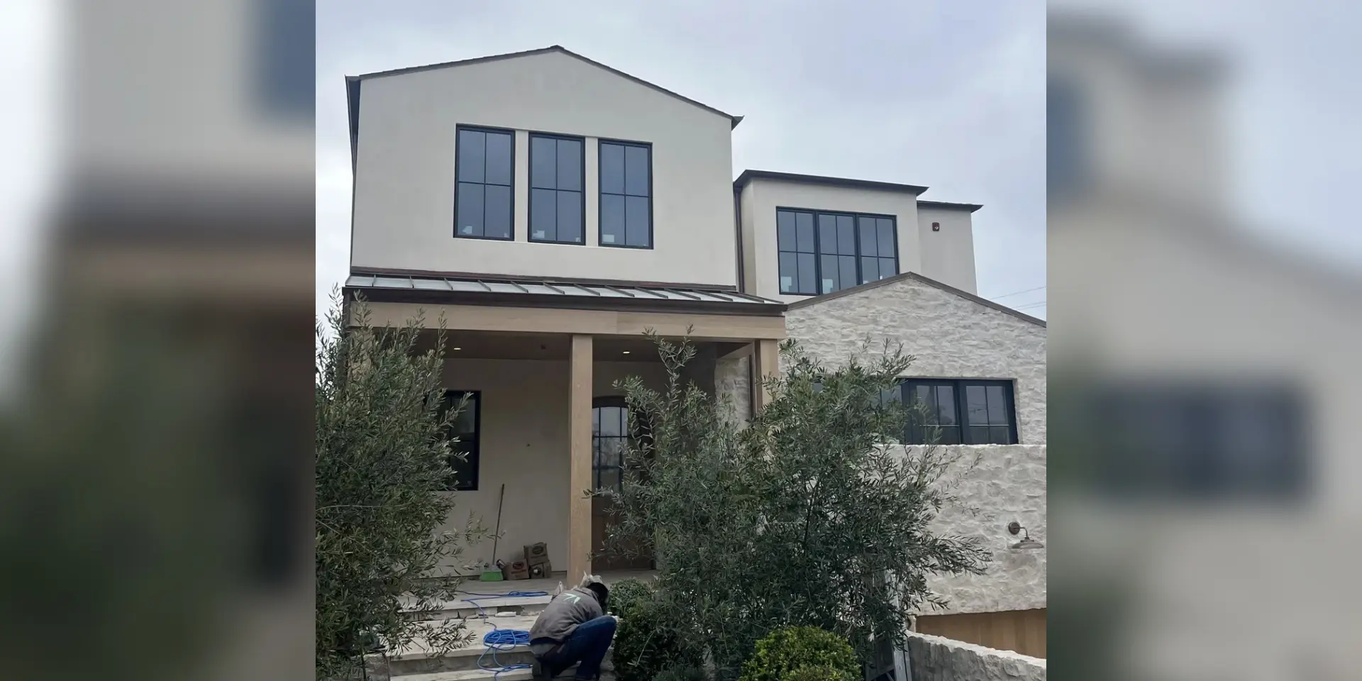 A house with two windows and a tree in front of it.